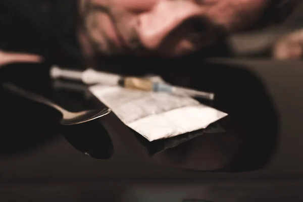 注射器 ヘロイン ビニール袋麻薬注射器やコカインやヒロインのクローズアップ背景に男の頭がぼやけています — ストック写真