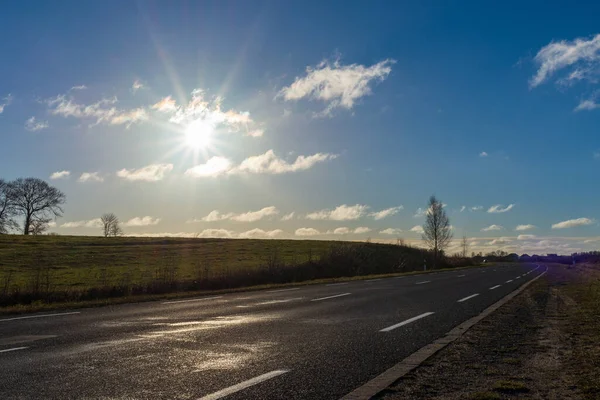 空のアスファルトの道路や太陽が天に昇るか 日没に行く古いアスファルトの道路 — ストック写真