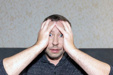 Stres atağı geçiren bir adam. Geniş açık gözler. Beyaz adam evde panik atak geçiriyor..