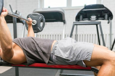 Yukarı itiyor. Spor salonunda tanınmayan spor adamı yalan söylüyor ve halteri kaldırıyor. Yaklaş..