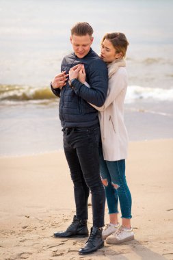 Genç çift sahilde eğleniyor ve eğleniyor. Bahar, sonbahar, sonbahar tatili..