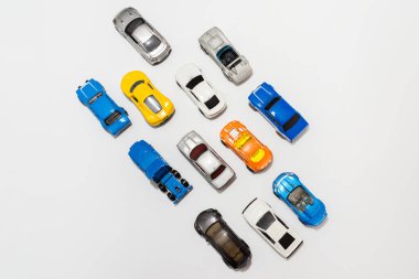 Beyaz arka planda birçok minyatür oyuncak araba. Yoldaki oyuncak araba grubu. Üst manzara, kopyalama alanı. Çoklu oyuncak arabalarla trafik sıkışıklığı kavramı.