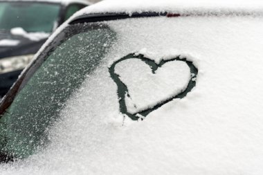 Kalp arabada. Kalp arabanın ön camına çizilmiş. Taze Noel karıyla kaplı..