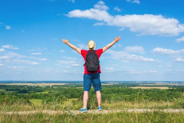 Orman manzarasına hayran olan genç bir adam. Arka planda vahşi ormanla birlikte yaz günü tek başına ayakta duran genç bir adam. Seyahat yaşam tarzı kavramı arka görünümü