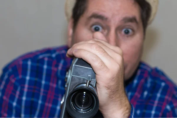 カメラを持つ男 カメラマンは レトロなカメラで映画を作る スーパーで撮影した再生シャツを持つ男8カメラ室内 クローズアップ トーン 選択的フォーカス グレーの背景 — ストック写真