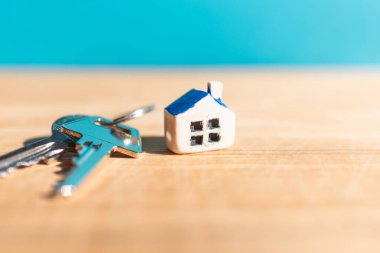 Minyatür yeni ev anahtarları ahşap mavi arka plan, gayrimenkul ve emlak işi kavramı. Kapanış, seçici odaklanma..