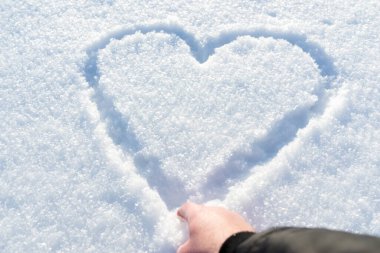 Beyaz kar üzerinde insan parmağı çizilmiş. Sevgililer Günü ya da fotokopi alanı olan Noel için güzel bir kış arkaplanı..