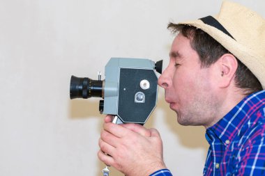 Komik, gülünç bir adam arka planda klasik bir sinema kamerası tutuyor. Adam ev filmi çekiyor. Seçmeli olarak film kameralarına odaklanıyor. Yakın çekim, kopyalama, yan görüş, kapalı çekim..