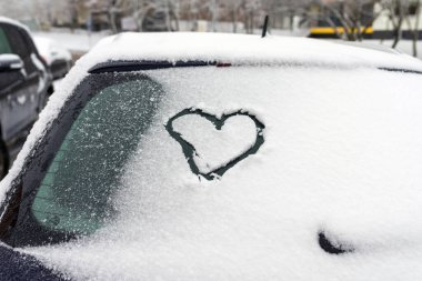 Kalp arabada. Kalp arabanın ön camına çizilmiş. Taze Noel karıyla kaplı..