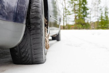 Kış kırsal yolundaki araba lastiği karla kaplı. Arabada paslanma ya da aşınma görülüyor. Seçici odak noktası, kopyalama alanı.