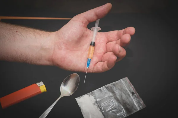 薬物の袋と暗い部屋に注射器で手を調節スプーンとライター — ストック写真