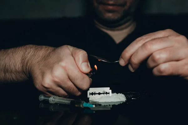 暗室で薬物中毒者 中毒だジャンキーはスプーンとライターで薬を準備してる 白い粉 カミソリと注射器 薬の概念 国際薬物乱用の日 — ストック写真