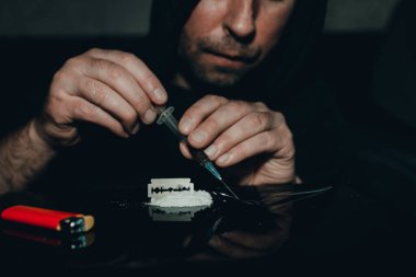 Şırınga eroin alıyor. Bağımlı karanlık oda. Uyuşturucu bağımlısı bir sonraki doz için hazırlanıyor..