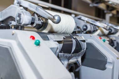 Bir tekstil fabrikasında pamuk ipliği üretimi. Tekstil kumaş üretim makineleri çalışıyor. İplik imalatı için sıra sıra otomatik makineler. Modern Tekstil Fabrikası Seçmeli Odaklanma.