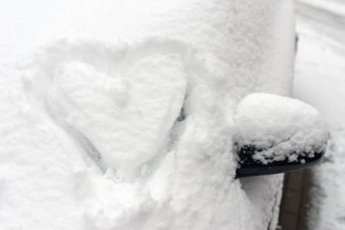 Kalp arabada. Kalp arabanın ön camına çizilmiş. Taze Noel karıyla kaplı..