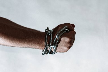 Erkek eli çelik bir zincir içinde. Çelik zincirler, gri bir duvardaki adamın elinde. Tonlama. Yaklaş, seçici odaklanma..