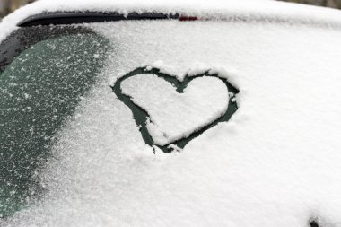 Kalbi donmuş ön cam, güzel kar zemini. Karlı araba camlarında kalp sembolü. Yakın plan, kopyalama alanı..