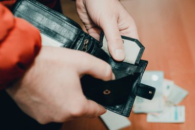 Mans elleri masanın yanında cüzdanı kontrol ediyor. Kapat, tonu ayarla. Bulanık arkaplan..