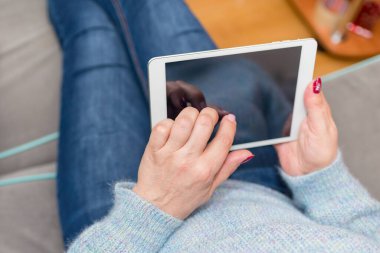 Tablet kullanan ve koltukta ya da koltukta oturan bir kadın. Oturma odasında tablet kullanan bir kadın. Seçili odak noktanız için metin modellemesi.