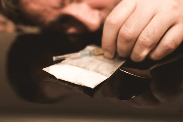 注射器 ヘロイン バッグ麻薬注射器やコカインやヒロインのクローズアップ 男の頭と手は背景に注射器で麻薬を取りますぼやけたトーンド — ストック写真