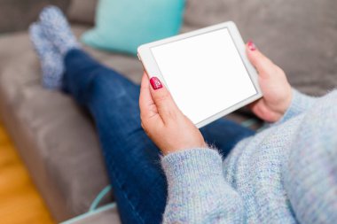 Evdeki kadın boş ekran ile tablet bilgisayarında rahatlıyor ve okuyor. Kapalı odaklan..