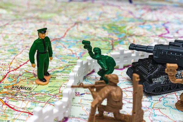 War and military concept. Group of miniature soldiers toy with tank lithuanian belarus map