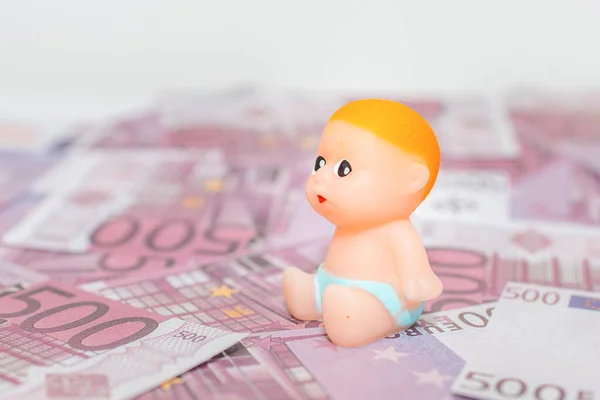 500 five hundred cash money miniature newborn infant baby toy sitting on a pile paper money background.Selective focus,copy space.