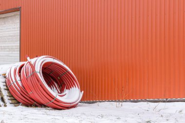 Sarılmış kırmızı plastik borular turuncu, arkaplan, seçici odak, kopyalama alanı yakınlarında saklanır..