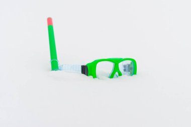 Kar eğlencesi. Yeşil dalış gözlükleri, beyaz karlı şnorkelle yüzen yeşil dalış seti soğuk kış gününde karların üzerinde yatıyordu. Dalış ekipmanları. Boşluğu kopyalayın..