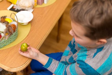 9 yaşında bir çocuk, annesi Paskalya yumurtası çırpmakla eğleniyor. Doğu bayramı için Litvanya 'da geleneksel bir eylem.