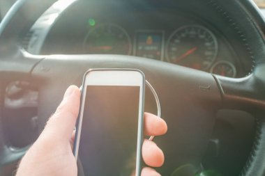 Baharda bir arabanın içinde cep telefonu kullanan bir adam..