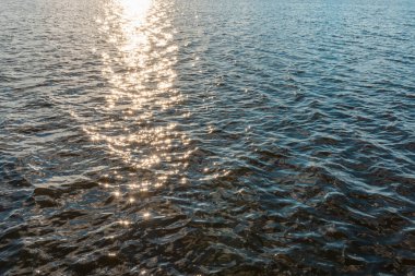 Güneş ışığının yansımaları gün batımındaki akşam suyunda parıldıyor..