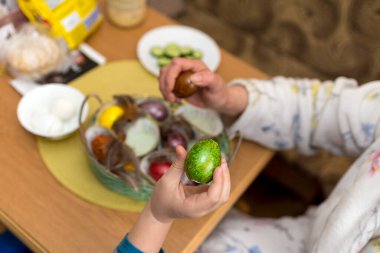 9 yaşında bir çocuk, annesi Paskalya yumurtası çırpmakla eğleniyor. Doğu bayramı için Litvanya 'da geleneksel bir eylem.