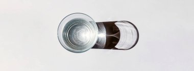 Camdan güneş ışığına. Banner, reklam, promosyon. Su, ışık kırılması nedeniyle beyaz arkaplanda güzel bir desen oluşturdu..