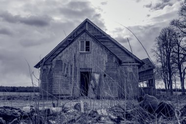 Eski ahşap ev, gece dramatik bulutlar. Terk Edilmiş Korku Evi. Akşamları ağaçların yanında. Siyah ve beyaz..
