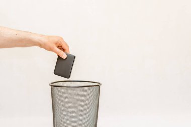 Harici sabit disk çöp kutusuna atılıyor, imha ve geri dönüşüm için. Beyaz, gri arkaplan, seçici odak, kopyalama alanı.