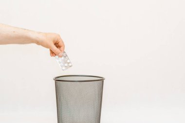 İlaç çöp kutusuna atılıyor, çöp öğütücü ve geri dönüşüm için. Beyaz, gri arka plan, seçici odak, kopyalama alanı..