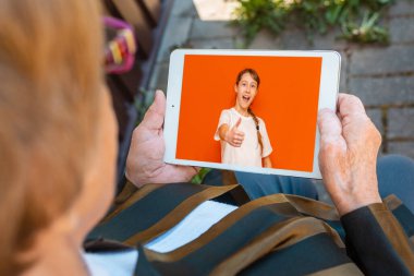 Elinde tablet bilgisayarla elinde torunun fotoğraf albümüne bakan mutlu yaşlı bir kadın. Teknoloji, yaş, hatıralar ve insan kavramı. Kapat..