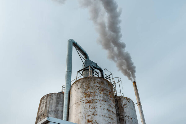 Chemical factory,smoke stack,CO2 greenhouse gas emissions coming from the smoking chimney pipe.Cloudy blue sky background.Copy space.