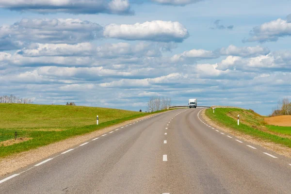 Cars asphalt road through the green agricultural fields background on a sunny summer day.