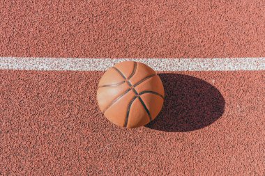 Lastik spor sahasında yatan eski turuncu top. Bahçedeki kırmızı zemin. Üst manzara, boşluğu kopyala..