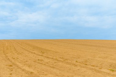 Tarım arazisi, yamaçta, yeni sürülmüş ve tarıma hazır. Mavi gökyüzü..