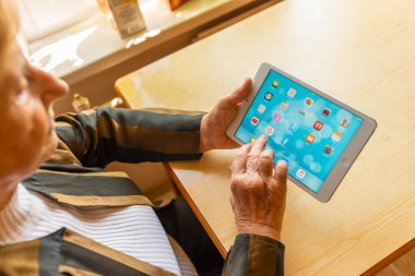 Üst düzey kadın internet üzerinden uygulama kullanarak alışveriş yapıyor, evinde oturuyor. Tablet bilgisayarlı yaşlı kadın. Seçici odaklanma. Yakın plan. Telsiai, Litvanya 05-08-2022.