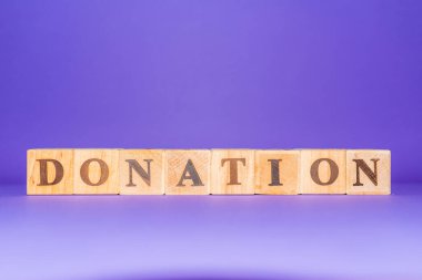 İş ve finans. Üzerinde DONATION yazan tahta küpler. Mor, veri peri rengi kapalı arkaplan. Boşluğu kopyala.