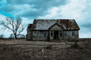 Eski ahşap ev, gece dramatik bulutlar. Terk Edilmiş Korku Evi. Geceleri tek bir ağaç var. Tonlanmış..