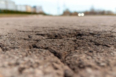 Sokakta hasarlı alfalt yol. Bulanık mavi gökyüzü arkaplan. Odak noktası, yakın plan..