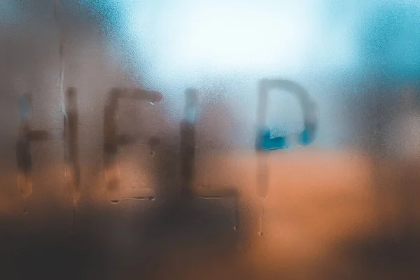 Help inscription on a dewy,foggy glass. Call for help.Selective focus.Blurred background.