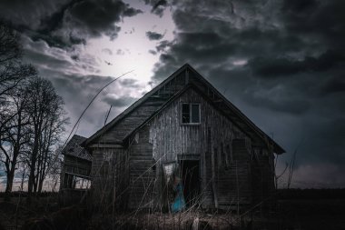 Eski ahşap ev, gece dramatik bulutlar. Terk Edilmiş Korku Evi. Geceleri ağaçların orada duruyor..