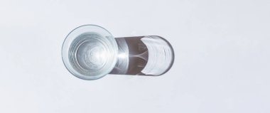 Camdan güneş ışığına. Banner, reklam, promosyon. Su, ışık kırılması nedeniyle beyaz arkaplanda güzel bir desen oluşturdu..