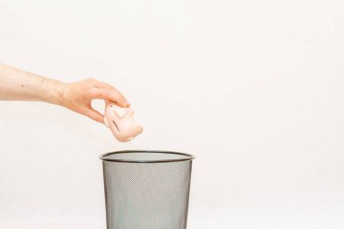 Pembe domuz kumbarası çöpe atılır, çöp tenekesi imha ve geri dönüşüm için. Beyaz, gri arka plan, seçici odak, kopyalama alanı..